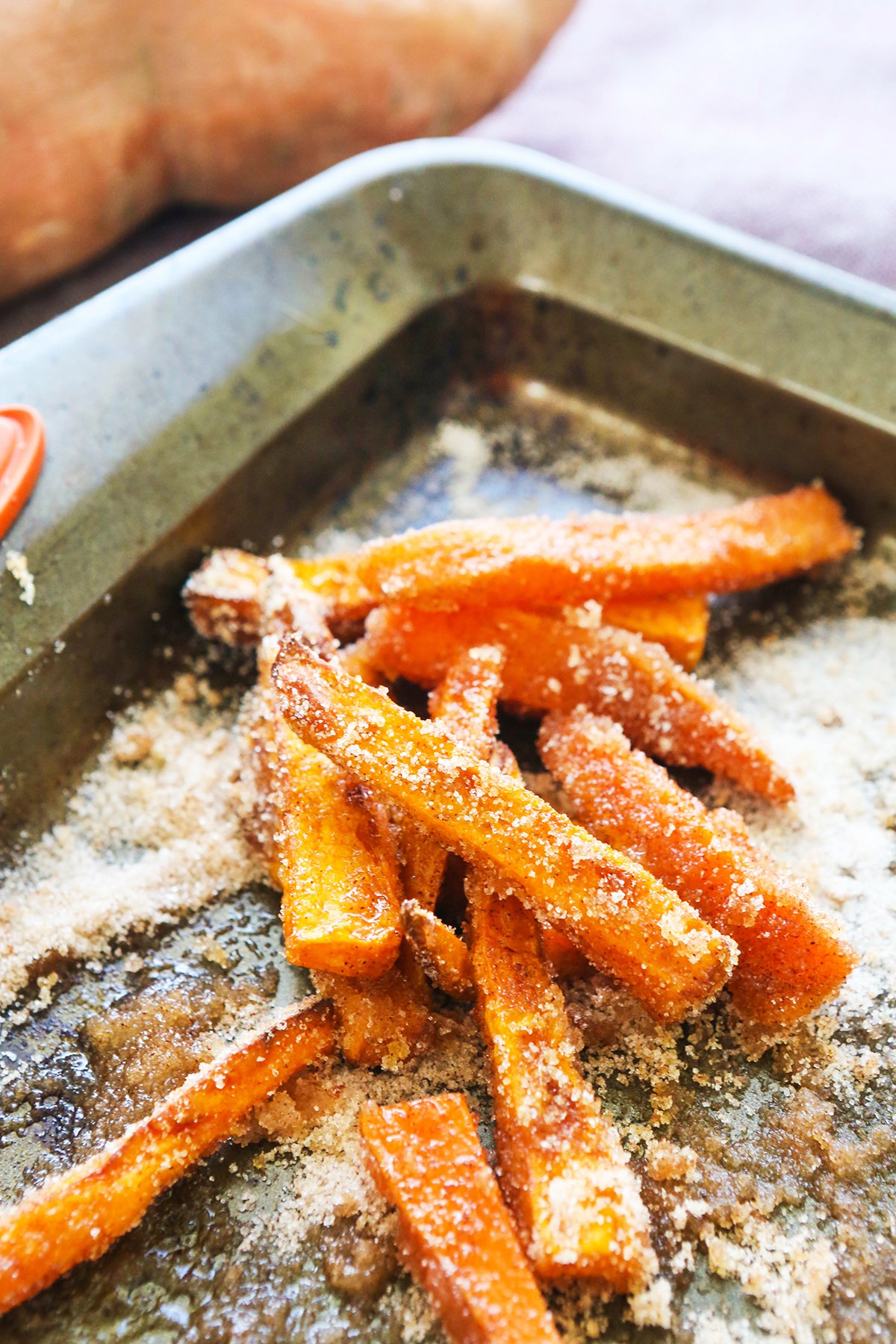 Sweet potato fries covered in sugar on a baking sheet.