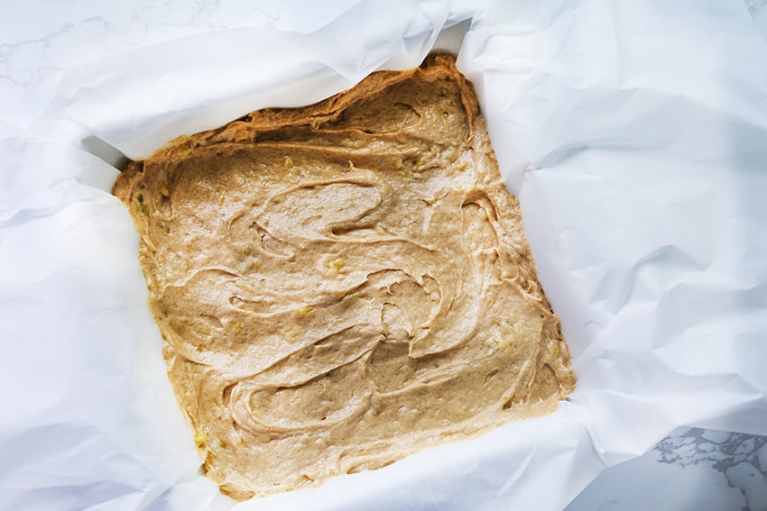 batter for banana bars spread into a parchment lined pan
