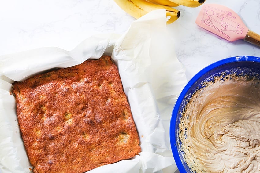 baked banana bars sitting next to a bowl of frosting