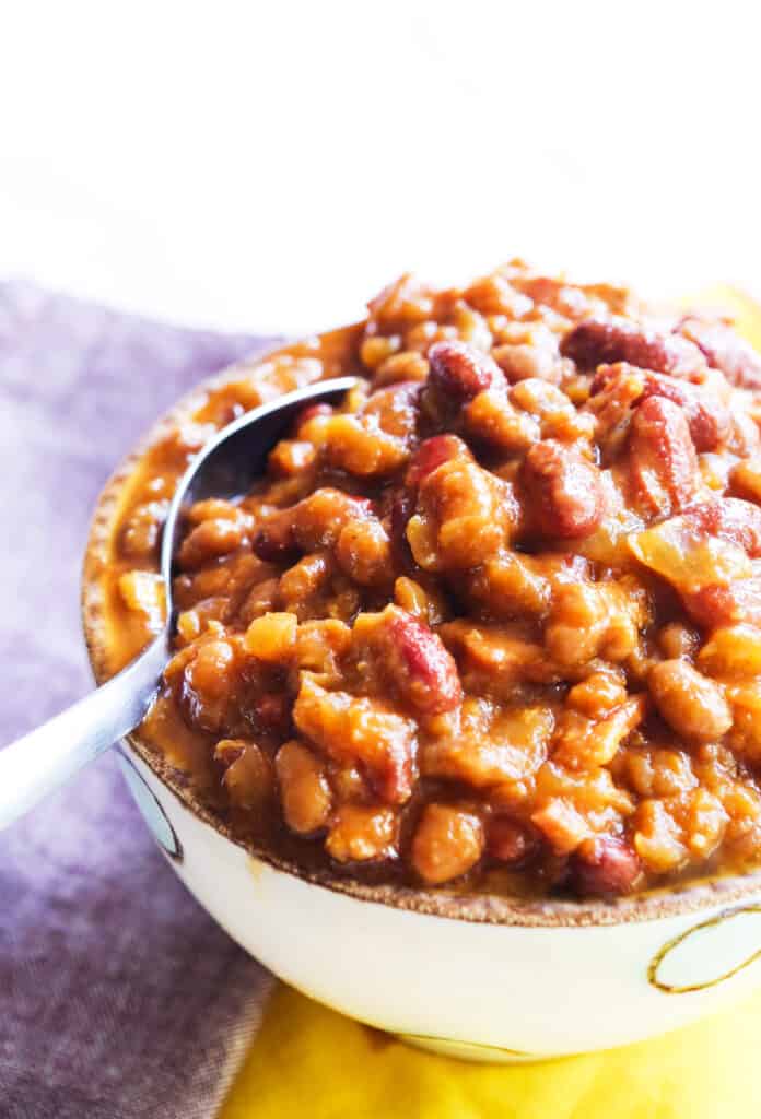 spoon sticking out of a bowl of crock pot baked beans