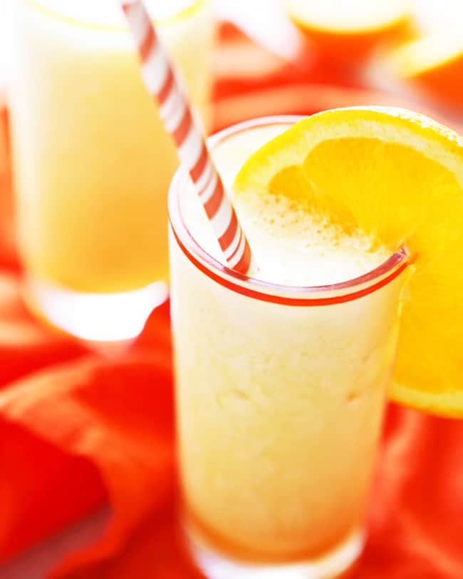 fun glass of frothy drink with an orange slice on edge