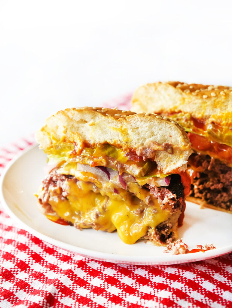A juicy lucy burger cut in half with melted cheese oozing out of it. 