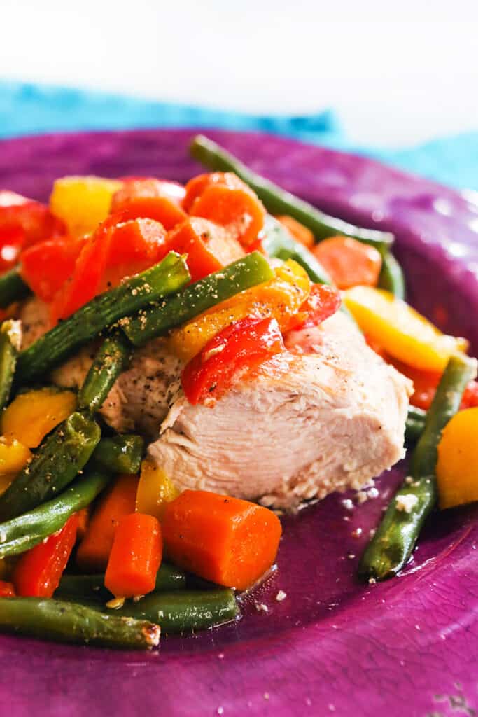 plate of cooked chicken topped with colorful veggies