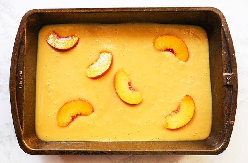 frozen peach yogurt in a pan with peach slices on top