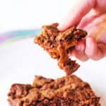 Close-up of caramel brownies with a hand holding a piece.