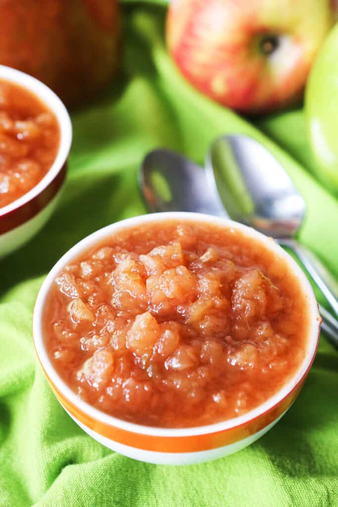 Two small bowls of crockpot applesauce with spoons. 