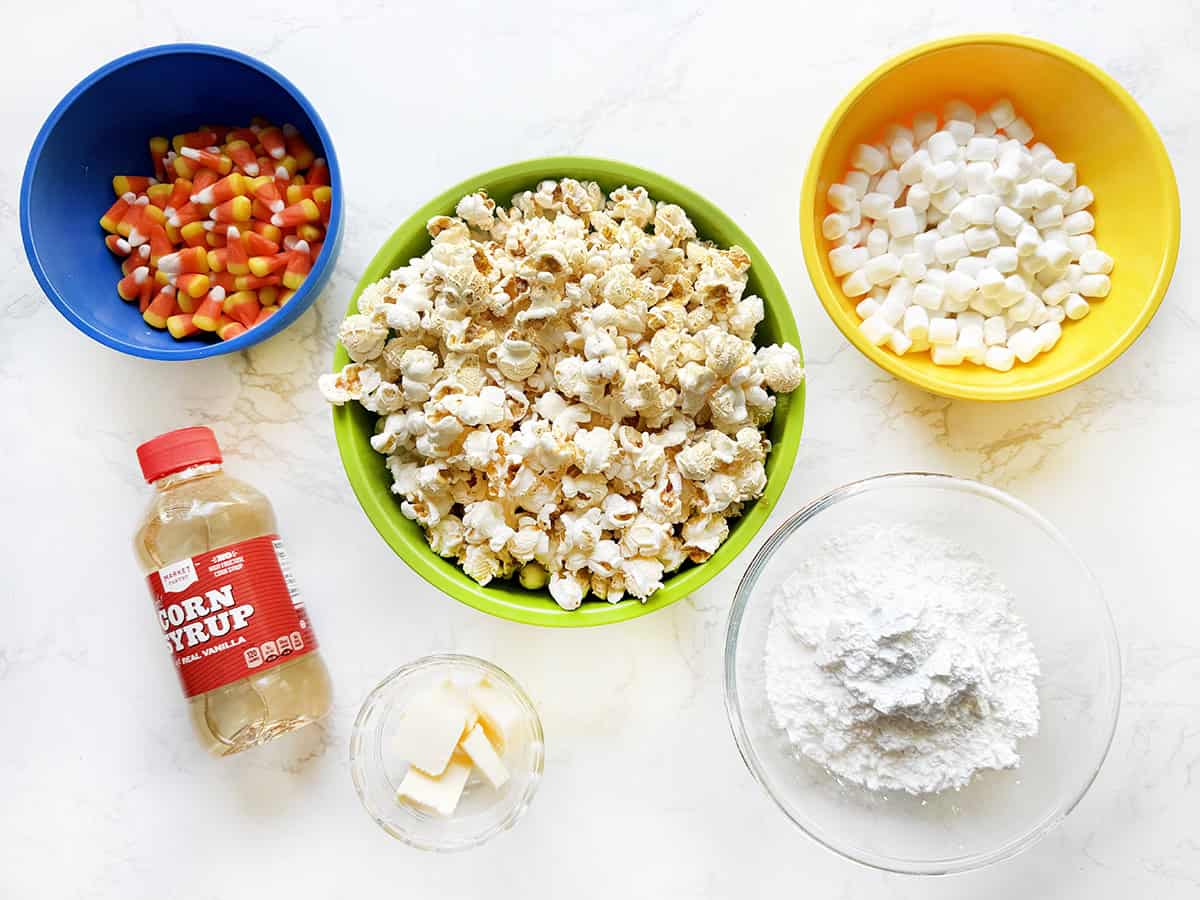 Ingredients for popcorn balls in bowls on a white counter.