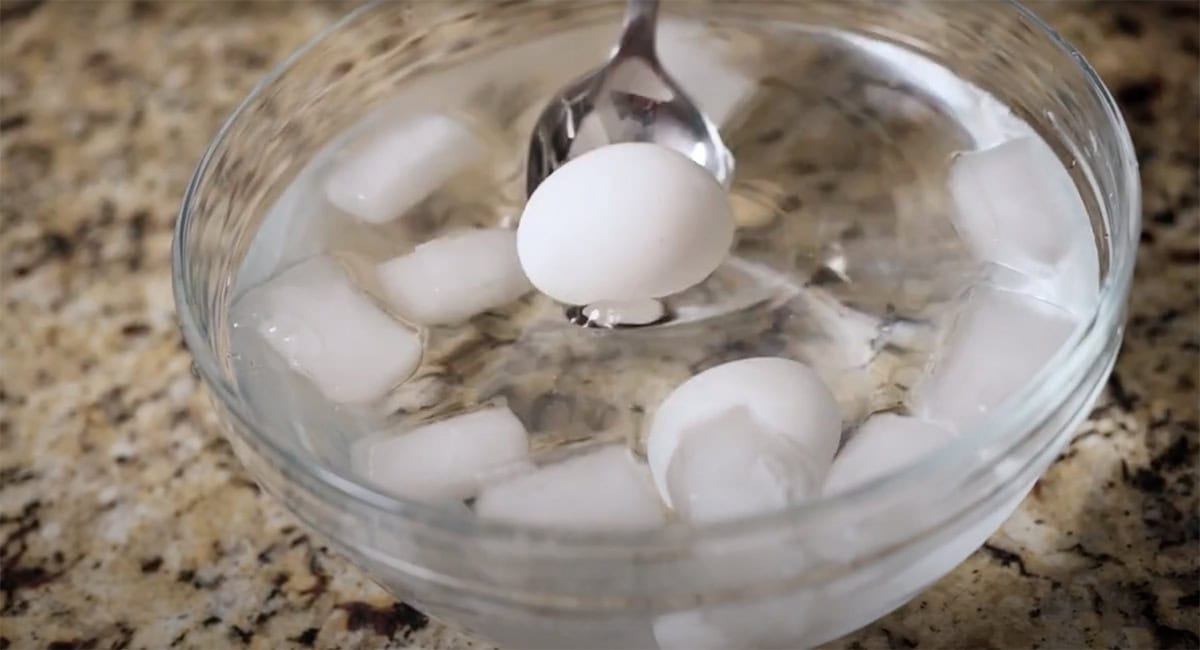 Spoon dropping an egg into an ice bath.