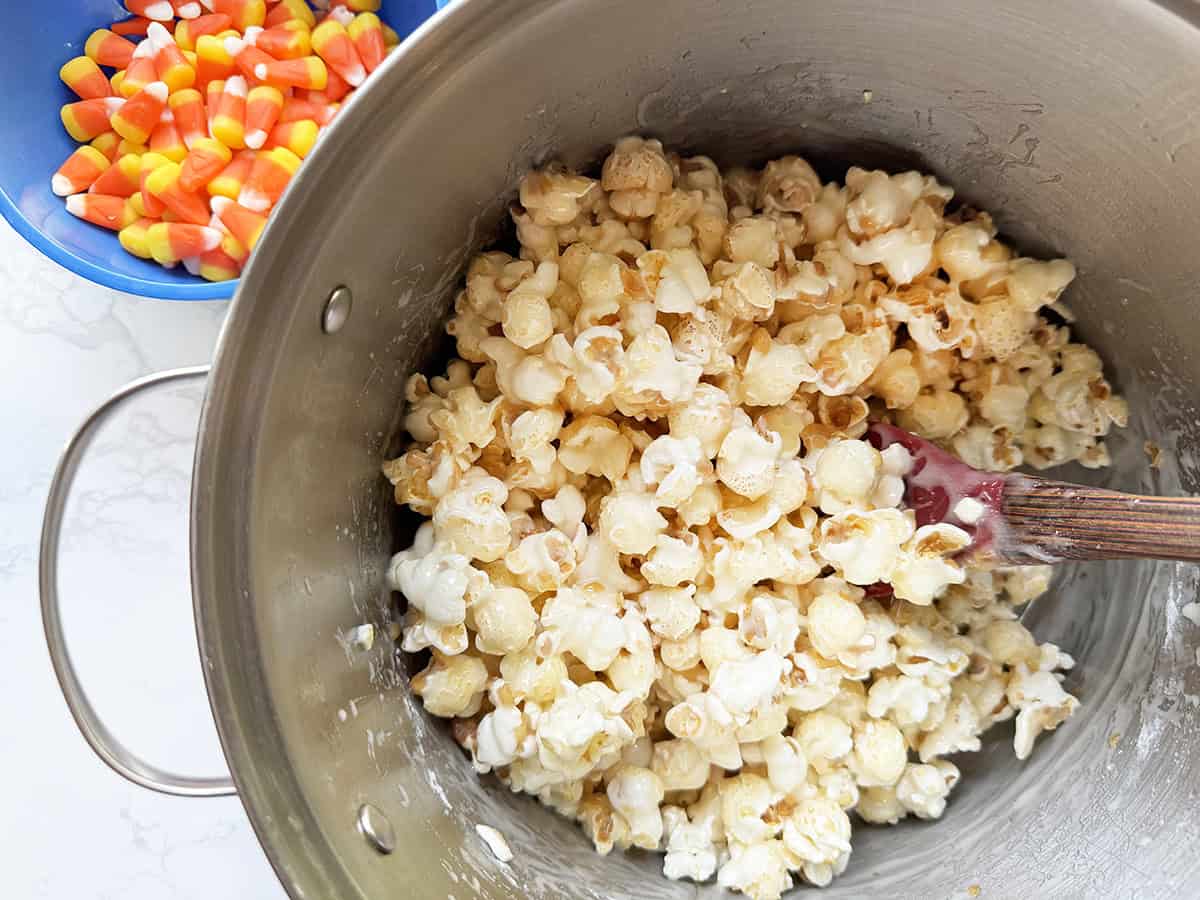 Pan filled with popped popcorn, next to a bowl of candy corn.