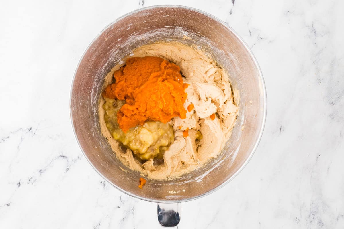Batter and pumpkin puree and mashed banana in a mixing bowl.