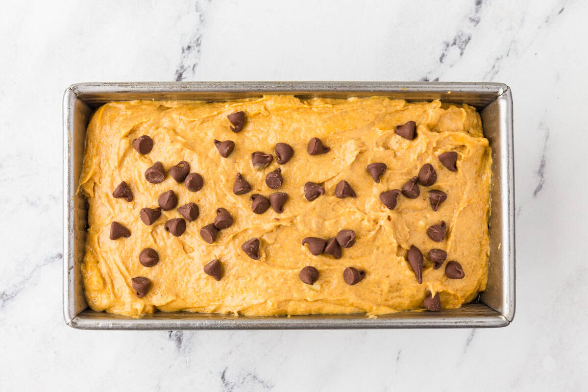 Top view of bread batter in a loaf pan with chocolate chips on top.