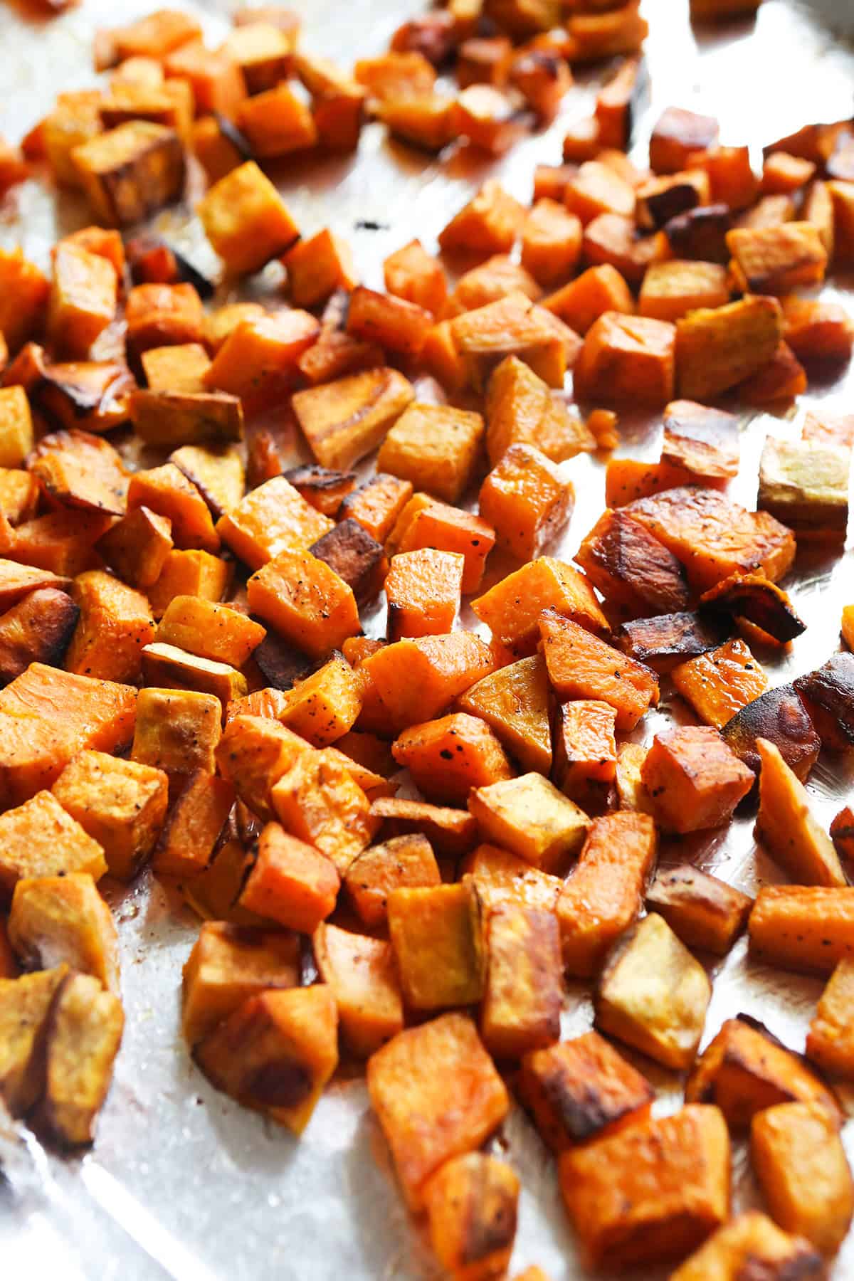 Roasted sweet potatoes on a parchment lined baking sheet.