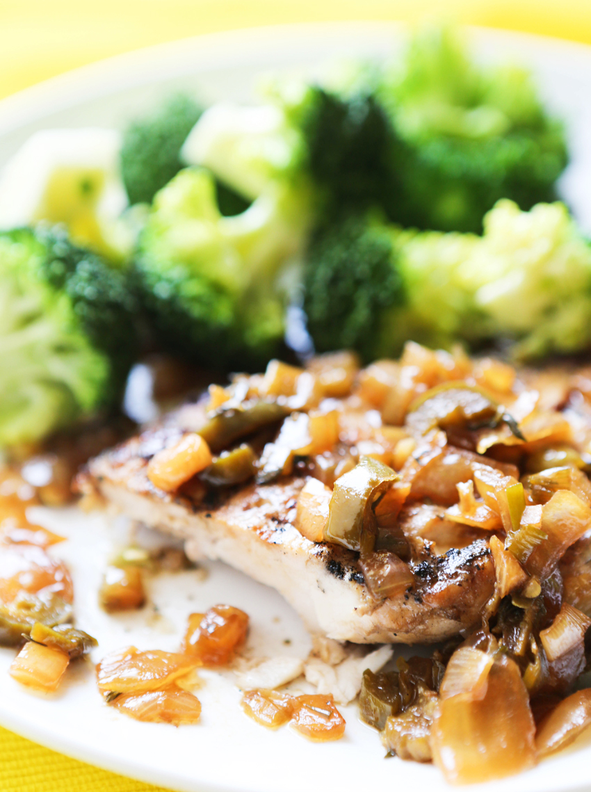 Chicken breast smothered in a jerk chicken sauce, next to a pile of cooked broccoli.