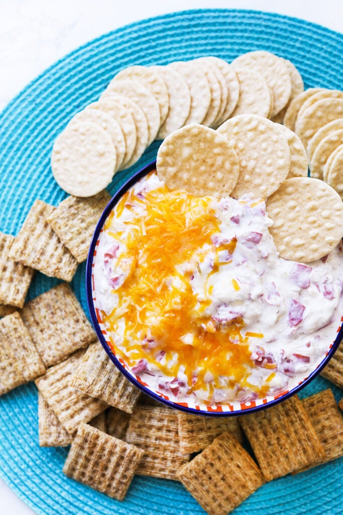 top view of crockpot reuben dip in a serving bowl with crackers surrounding it