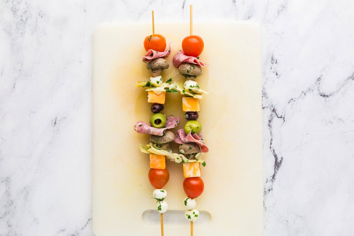 Two skewers on a cutting board loaded with delicious ingredients.