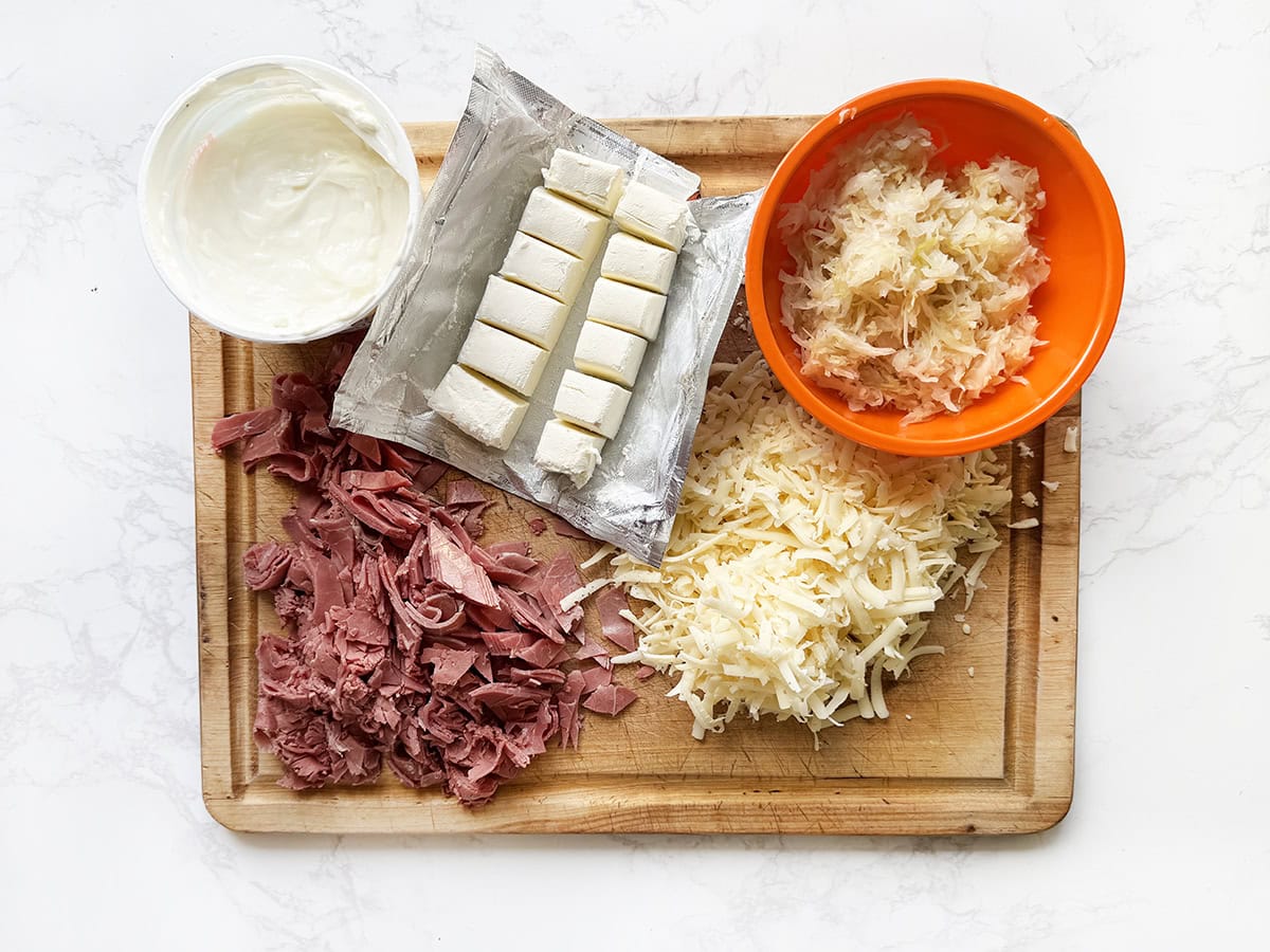 Ingredients for reuben dip on a cutting board.