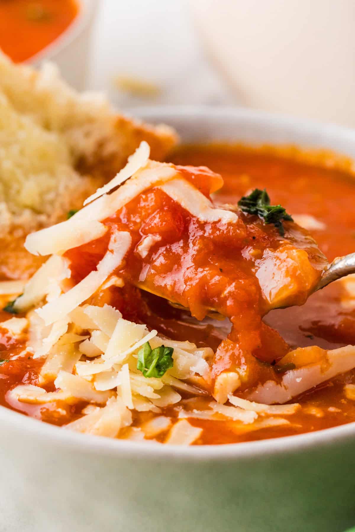 Spoon lifting a bite of tomato soup out of a bowl.