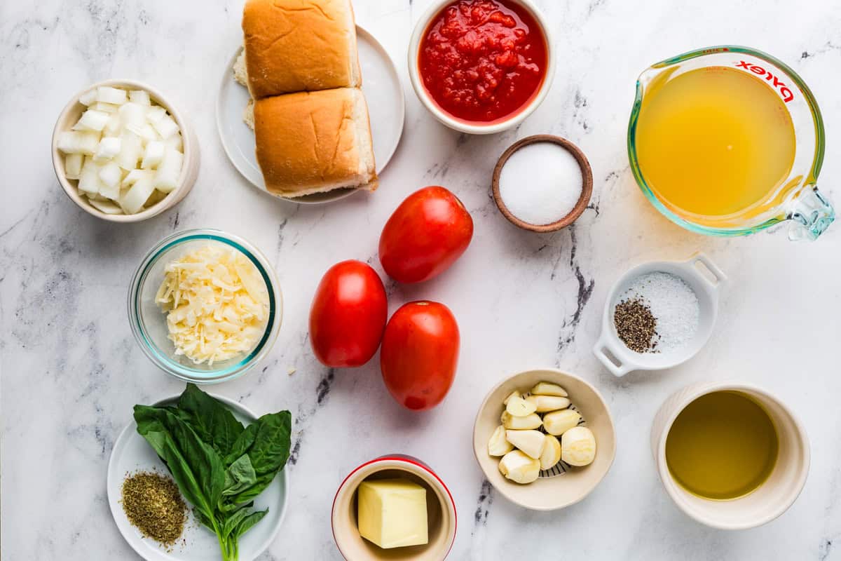 Ingredients for tomato soup on a white counter.