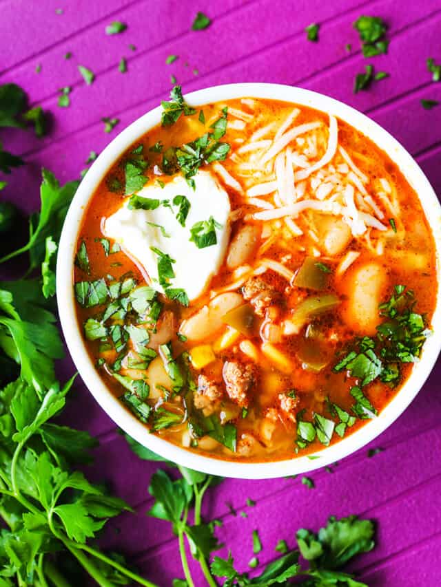 Top view of a bowl of white chicken chili with cilantro sprinkled on top and a dollop of sour cream.