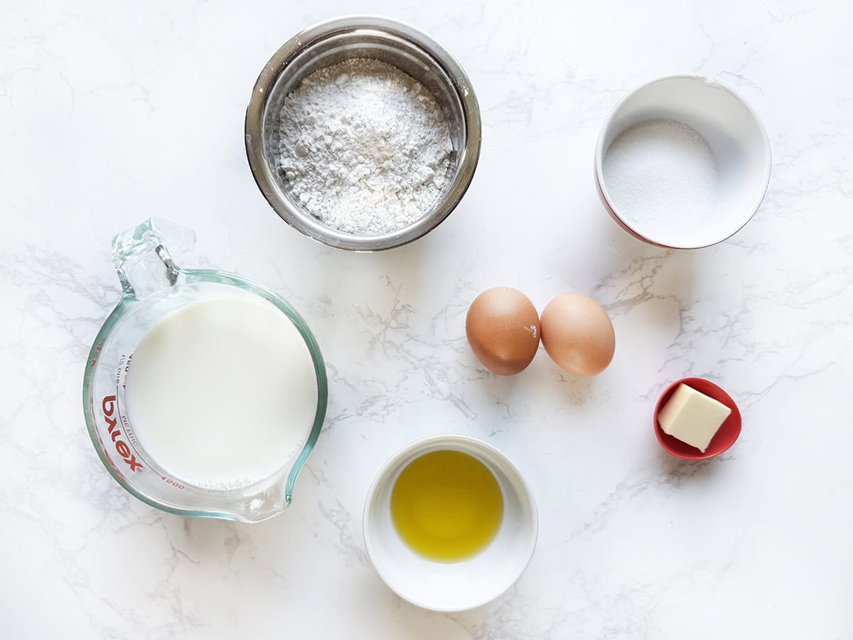 Ingredients for swedish pancakes lined up on a white counter.