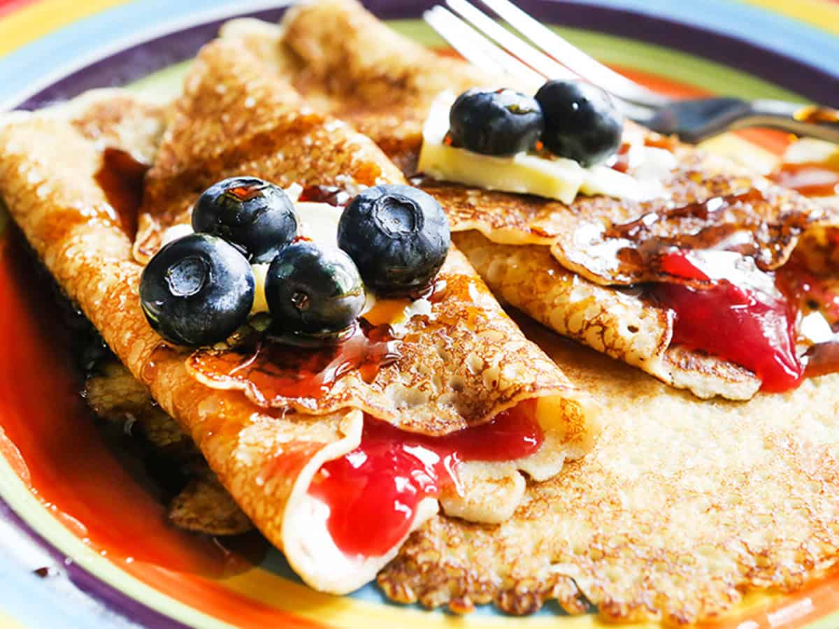 Swedish pancake with a red jelly filling, topped with butter and blueberries.