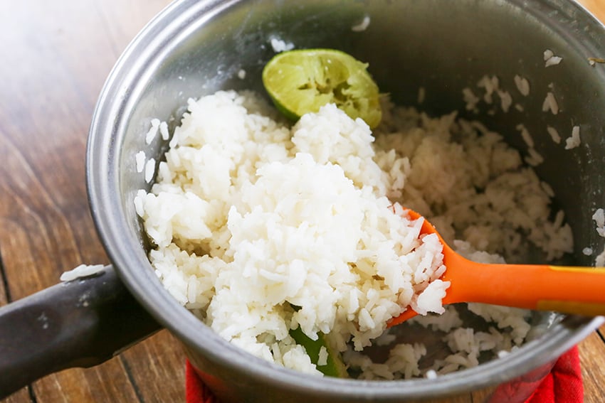cooked rice in a saucepan with half squeezed lime