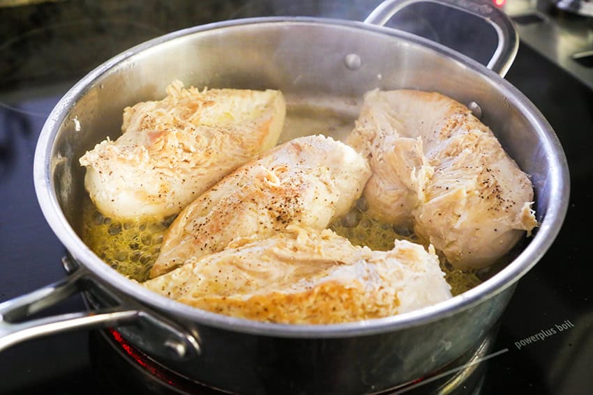 Baked chicken breasts sizzling in a skillet, golden and tender, perfect for a healthy meal.