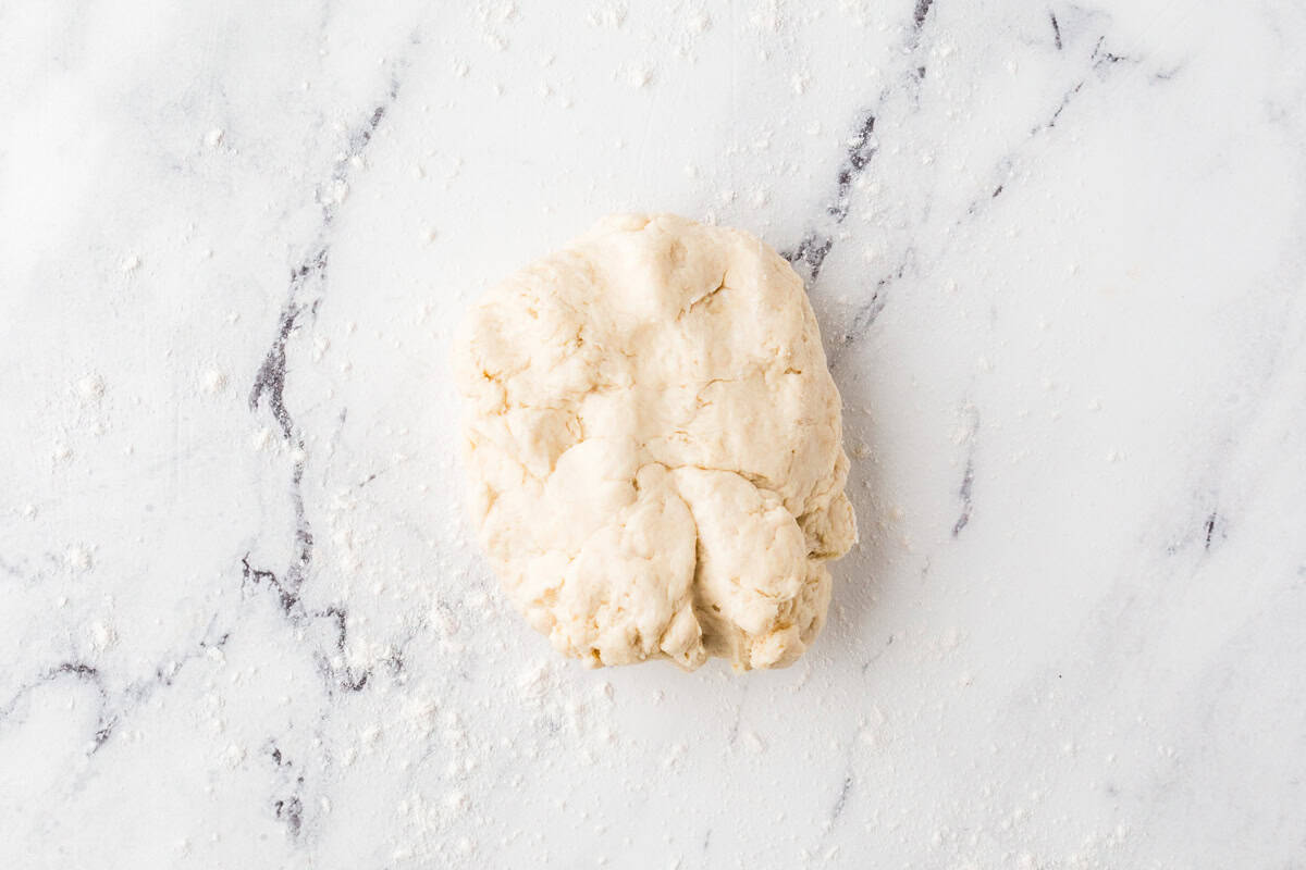 Blob of pizza dough on a white counter.