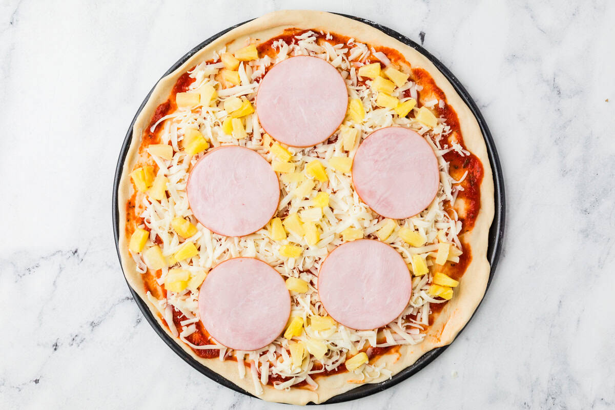 Top view of pizza before baking, on a pizza pan.