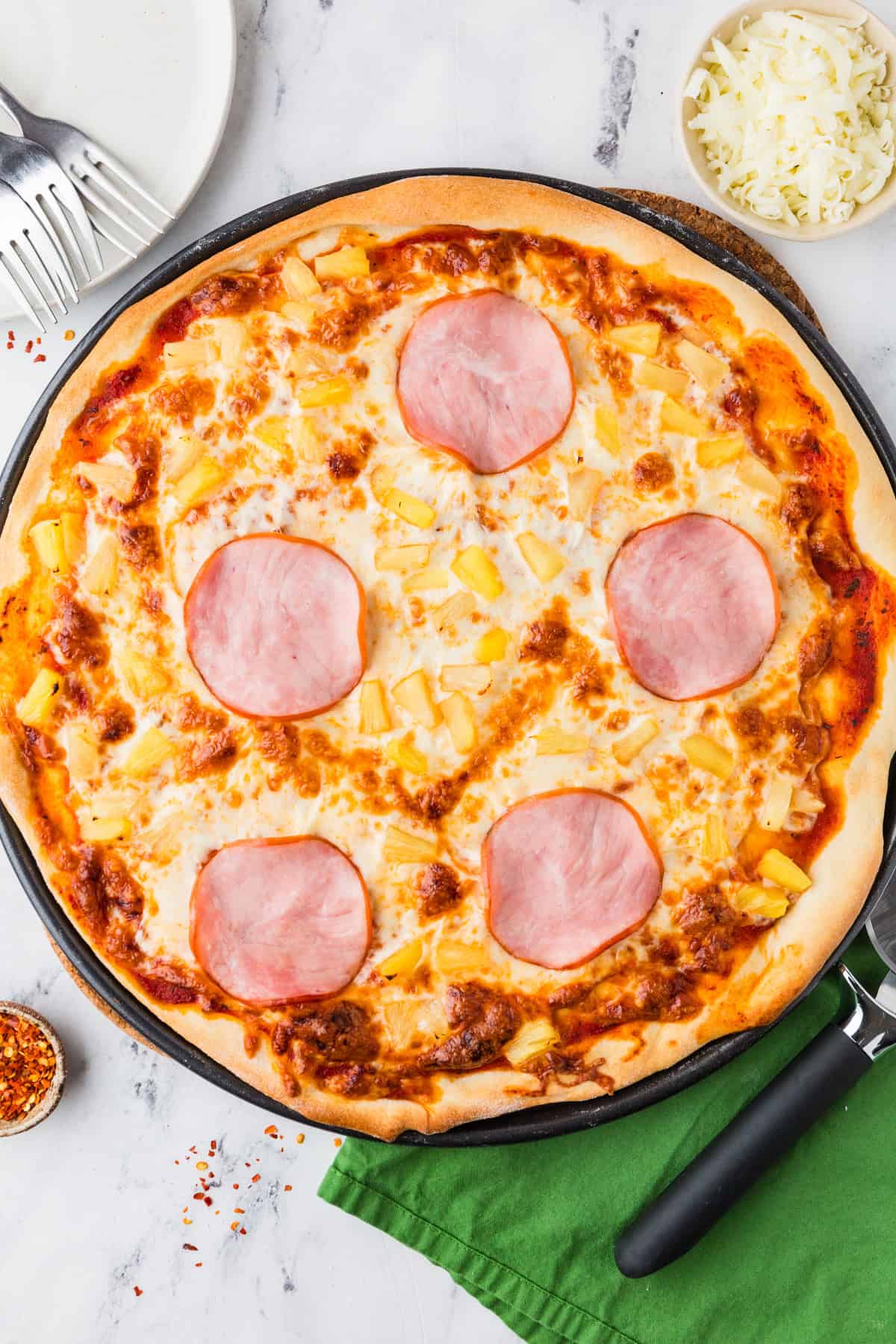 Baked canadian bacon pineapple pizza on a baking sheet.