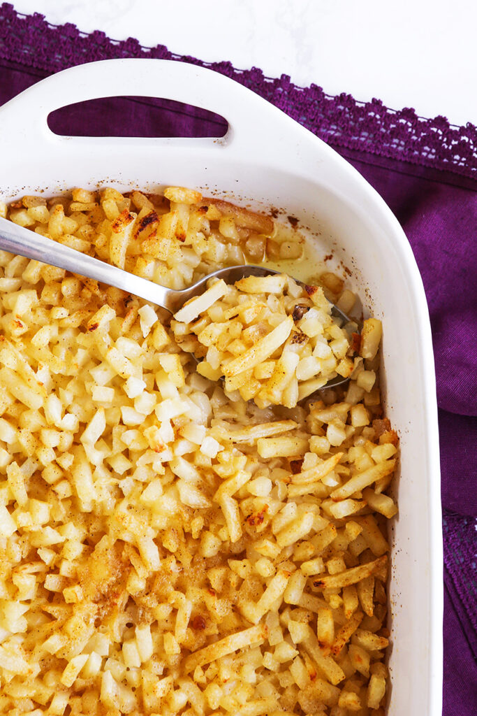 spoonful of hashbrown potatoes coming out of serving dish