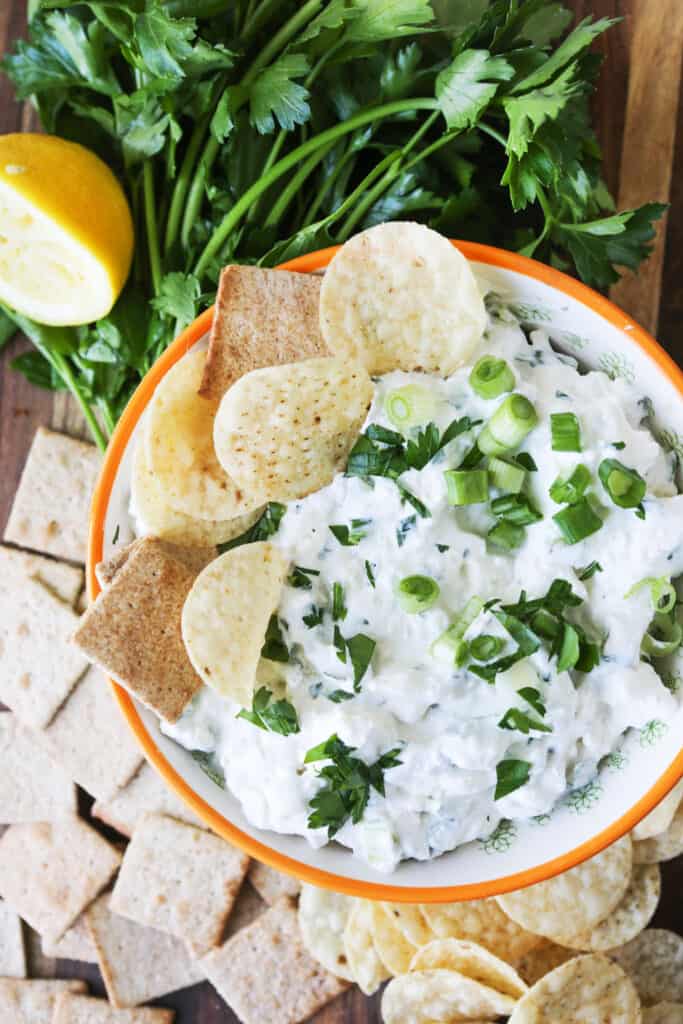 Feta cheese dip in a bowl with crackers and chips tucked into the side. 