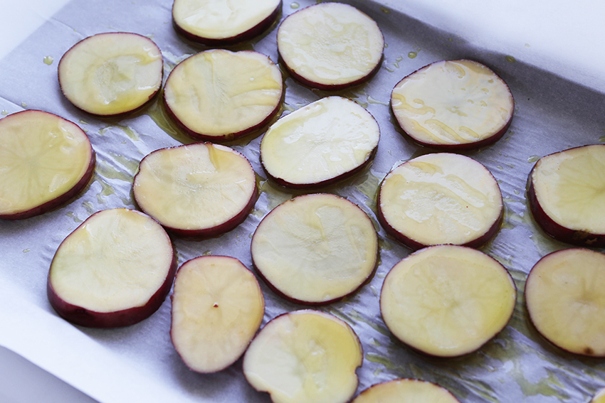 potato rounds lined on baking sheet with olive oil drizzled over tops
