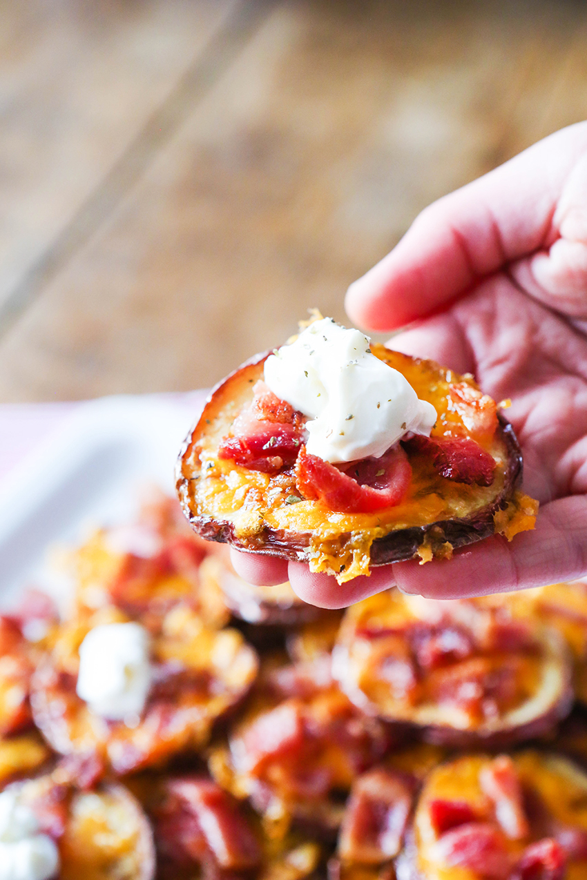 Hand holding a loaded baked potato round in fingers.