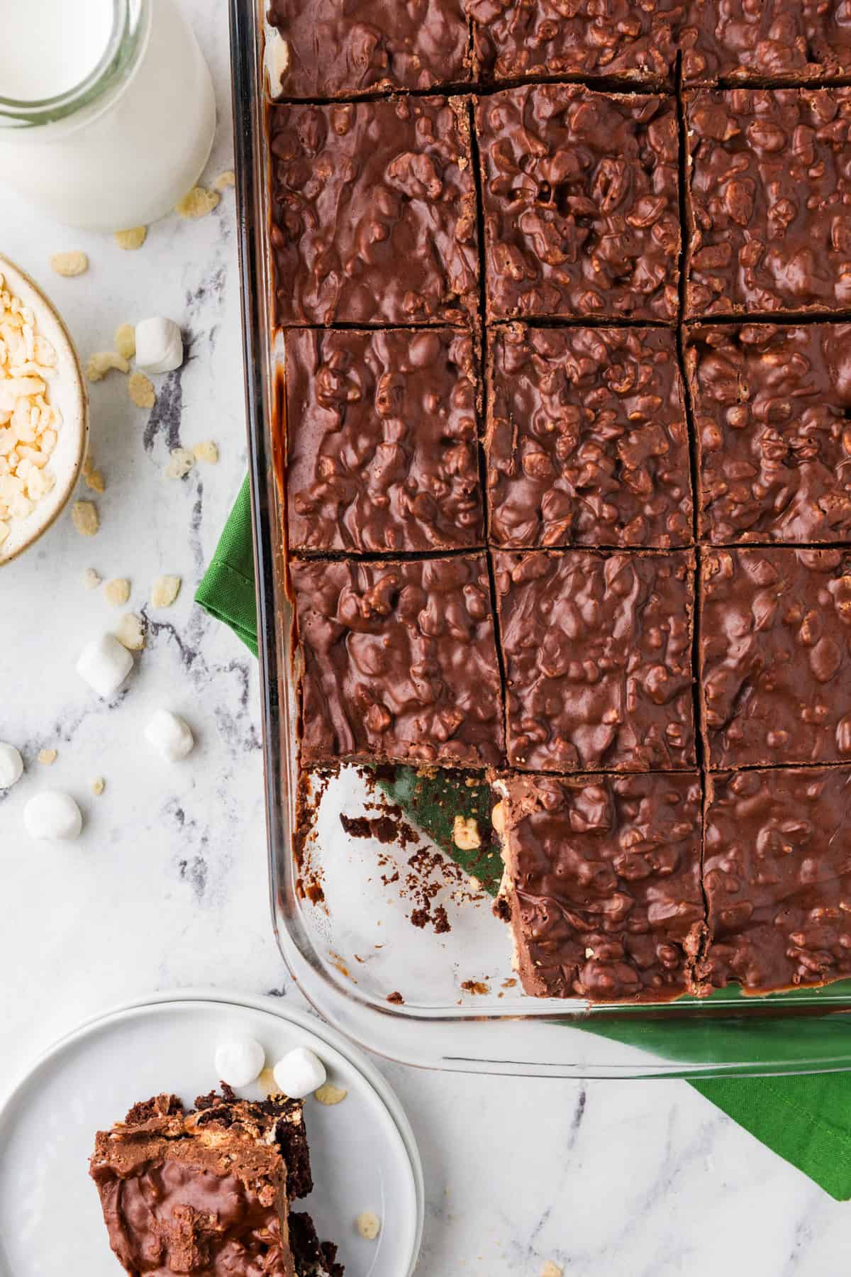 Top view of a pan of brownies with one removed and sitting on a nearby plate.