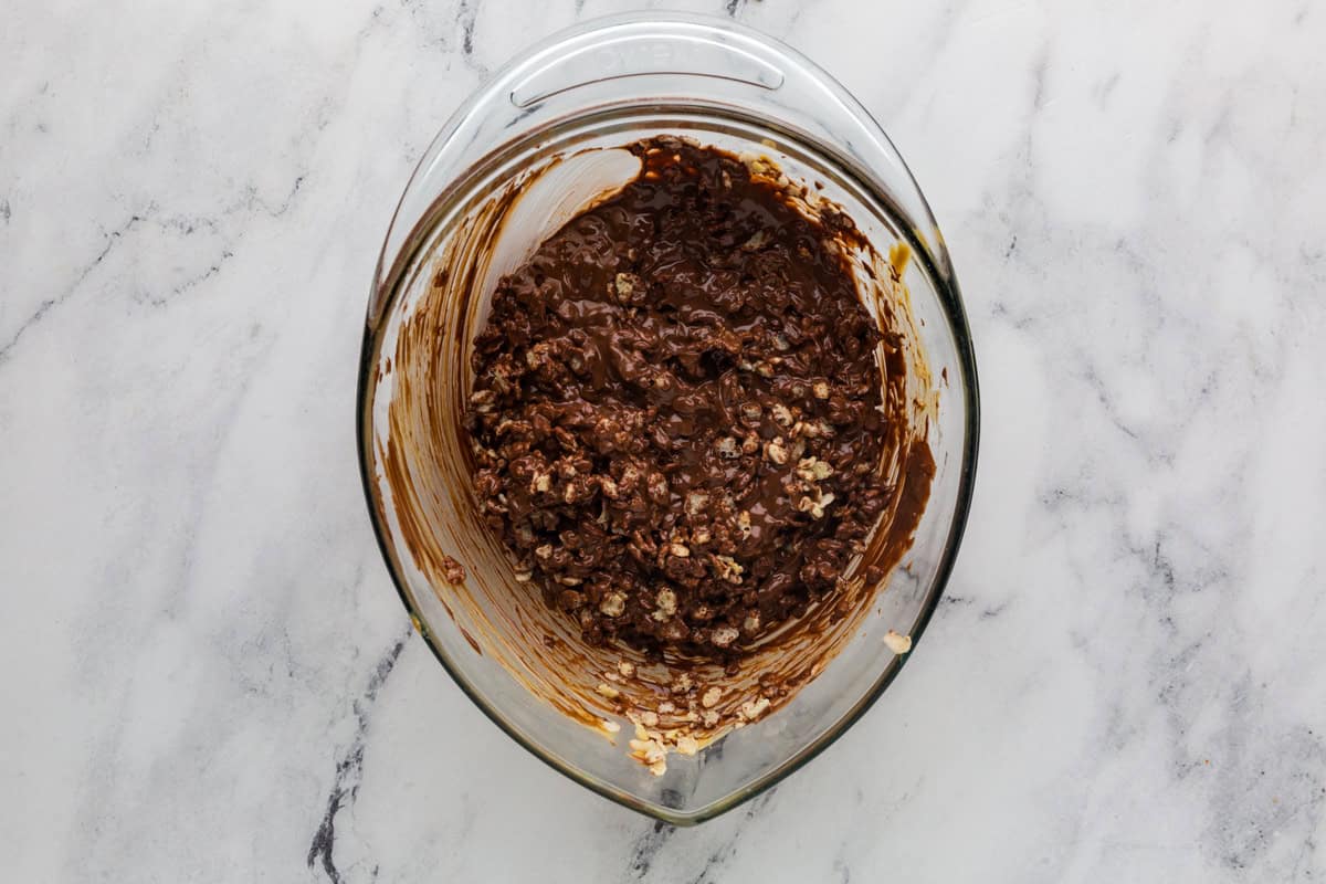 Rice krispies coated with chocolate in a glass mixing bowl.