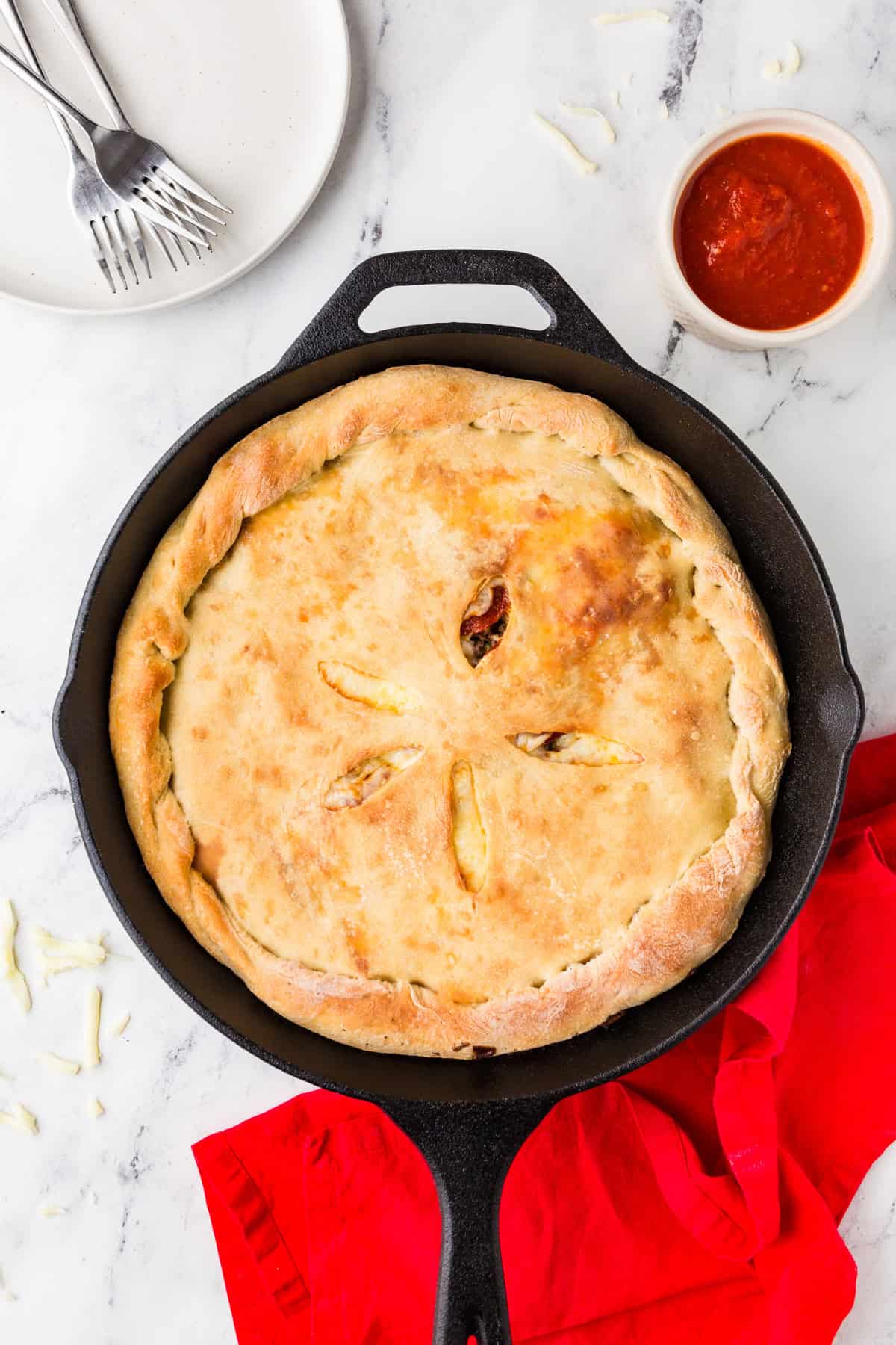 Top view of a baked calzone inside a cast iron pan.