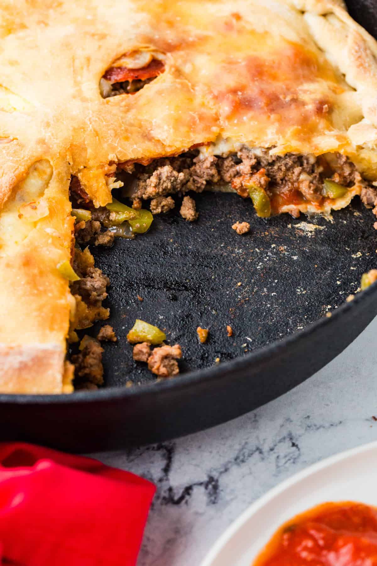 Calzone inside a pan, with a few slices removed revealing meat and veggies.