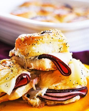 Close-up of a ham and cheese slider with melted cheese and sliced ham on Hawaiian roll.