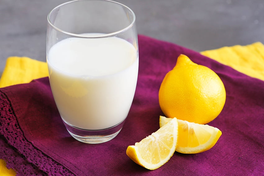 glass of buttermilk next to lemon wedges