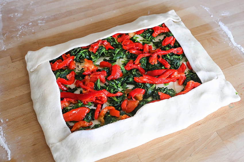 stromboli calzone dough with peppers and spinach inside, ready to roll up