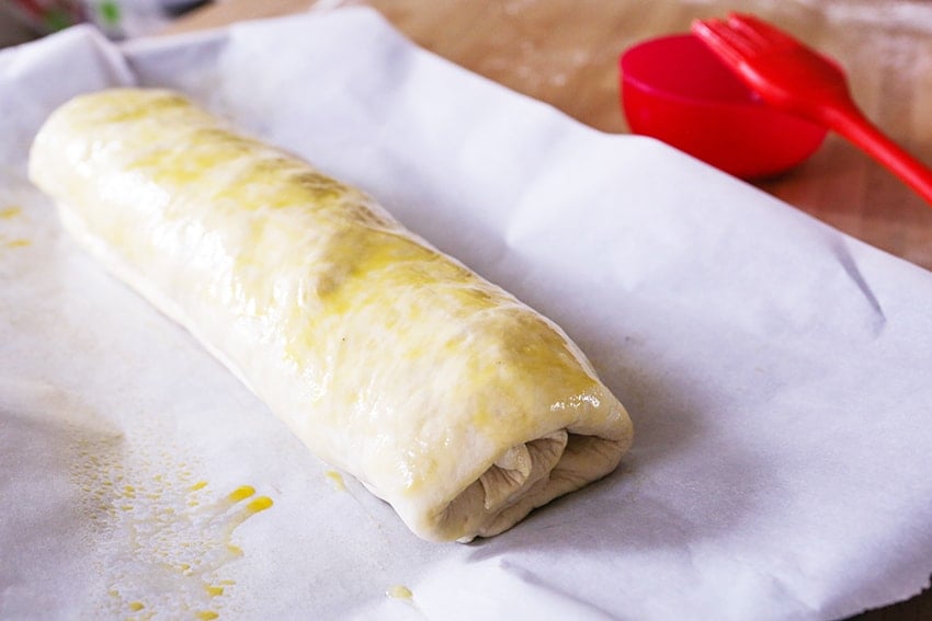 stromboli log rolled up on a baking sheet and brushed with egg