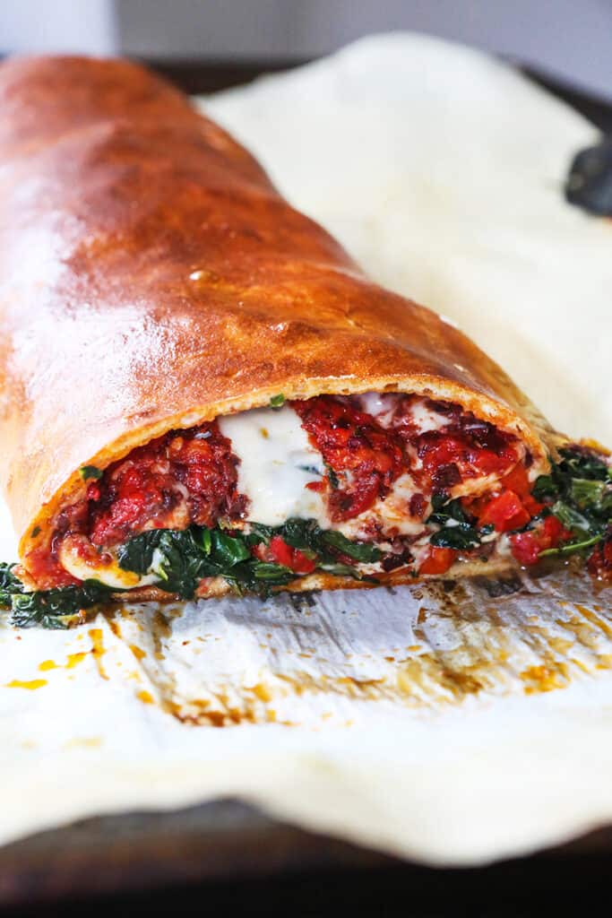 A slice removed from a cheesy vegetable calzone. 