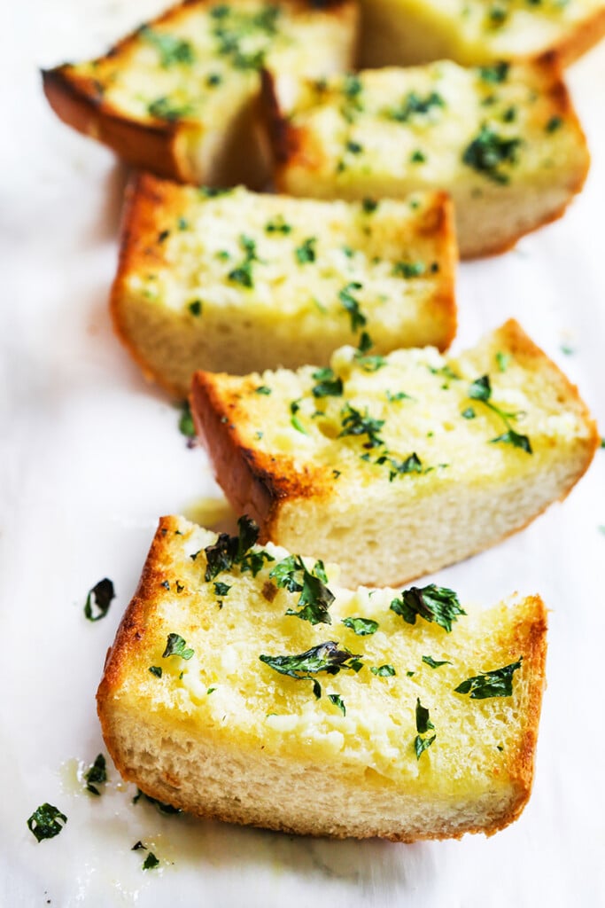 Garlic bread french bread cut into slices and garnished with parsley. 