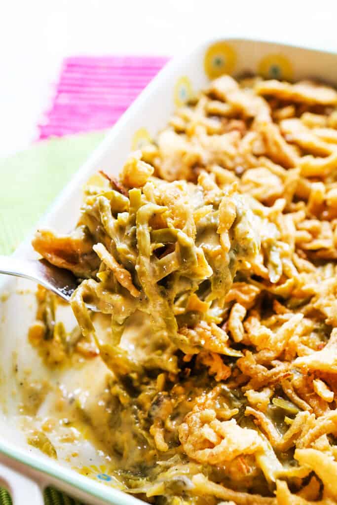 large spoonful of green bean casserole being removed from baking dish