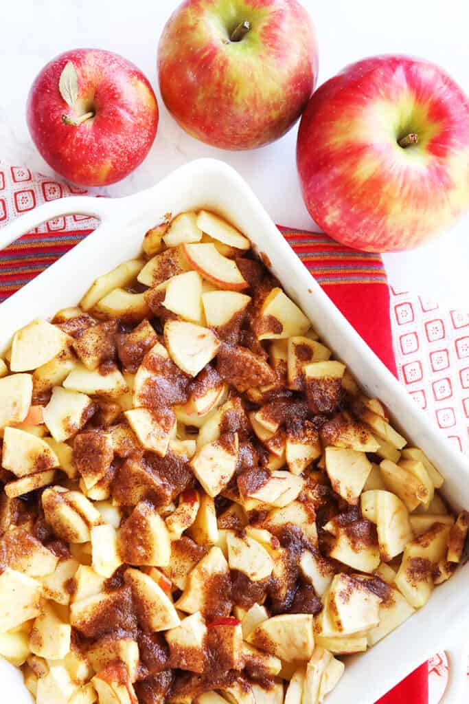 baked apple slices covered with a cinnamon sauce in a baking dish