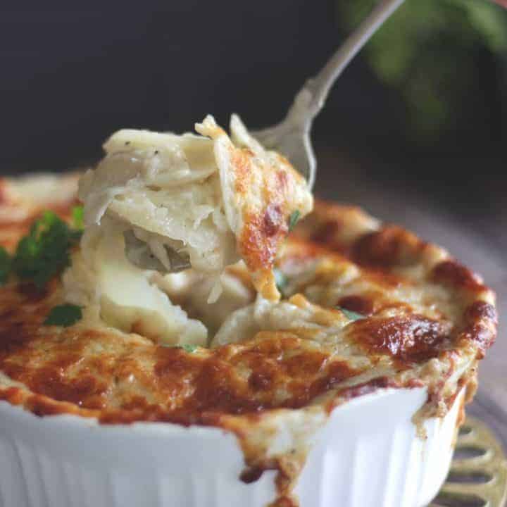 spoon coming out of a ramekin  filled with gluten free scalloped potatoes