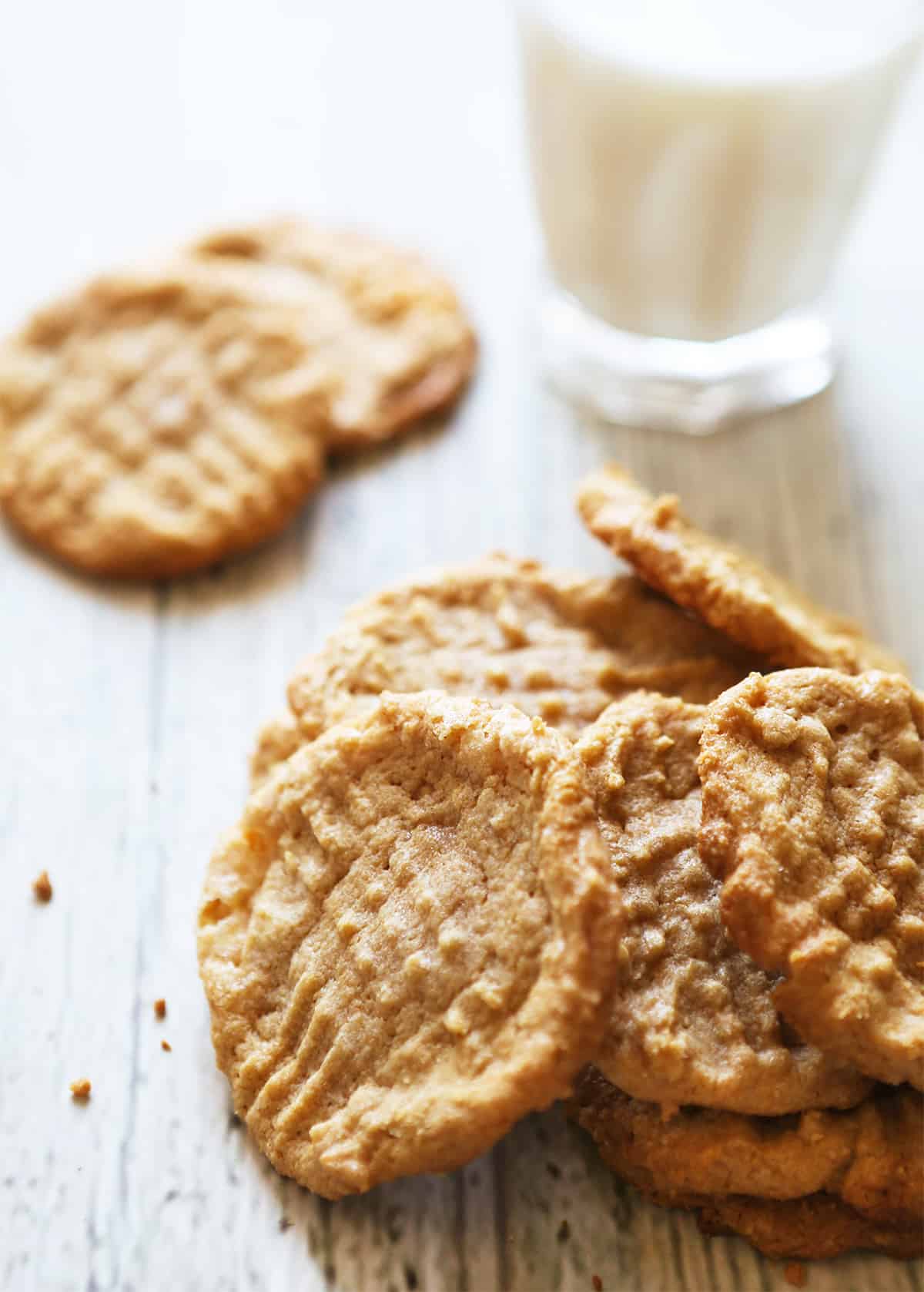 stack of peanut butter cookies sitting next to a glass of milk