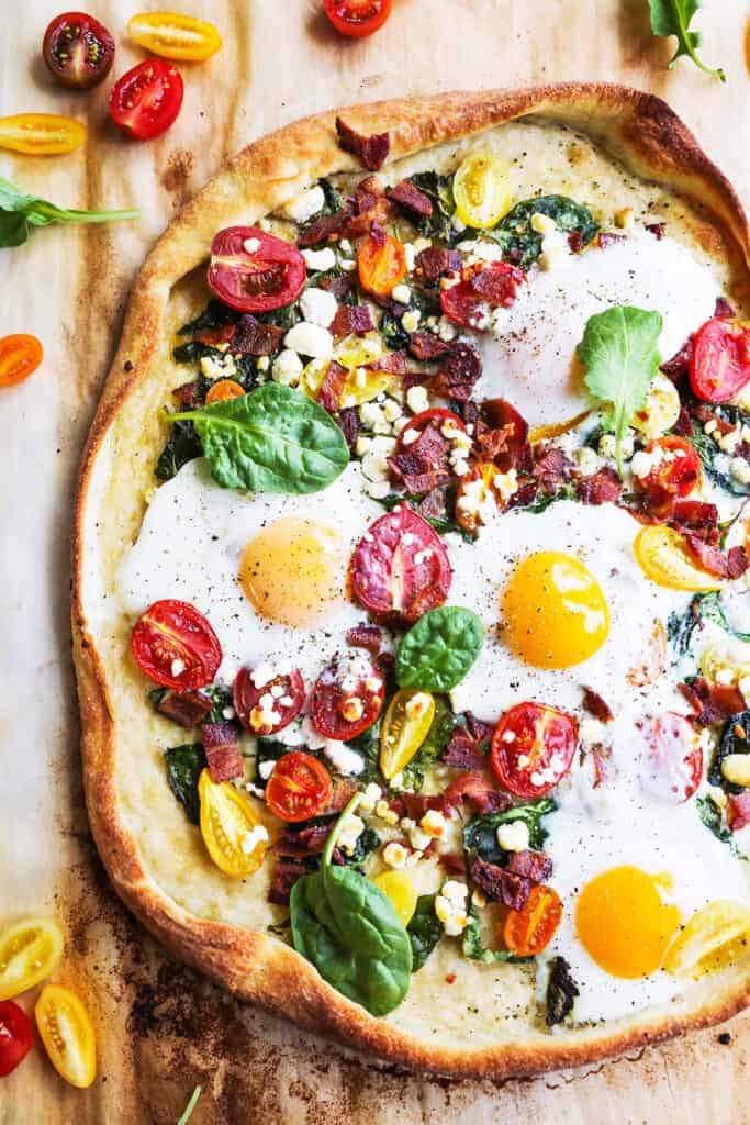 Baked breakfast pizza sitting on parchment paper ready to be sliced up.