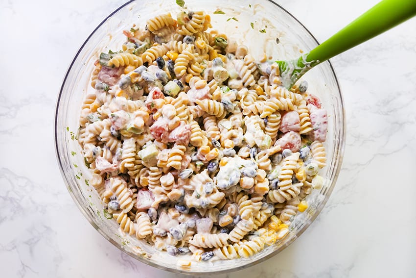 creamy pasta salad mixed in a bowl with a serving spoon